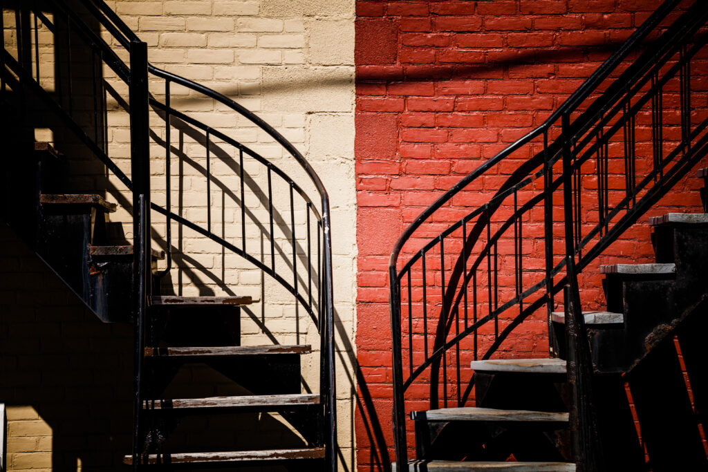 Symmetrical staircases against a brick wall painted half red and half white