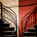 Symmetrical staircases against a brick wall painted half red and half white