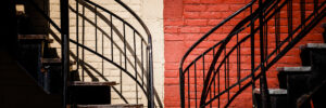 Symmetrical staircases against a brick wall painted half red and half white