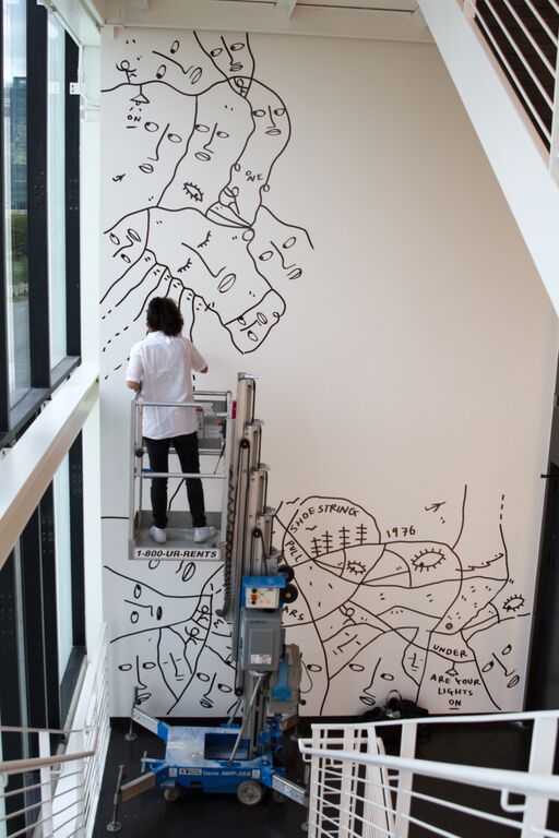 artist shantell martin on a lift painting black and white faces