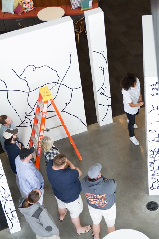 group of people watching artist draw on large white walls