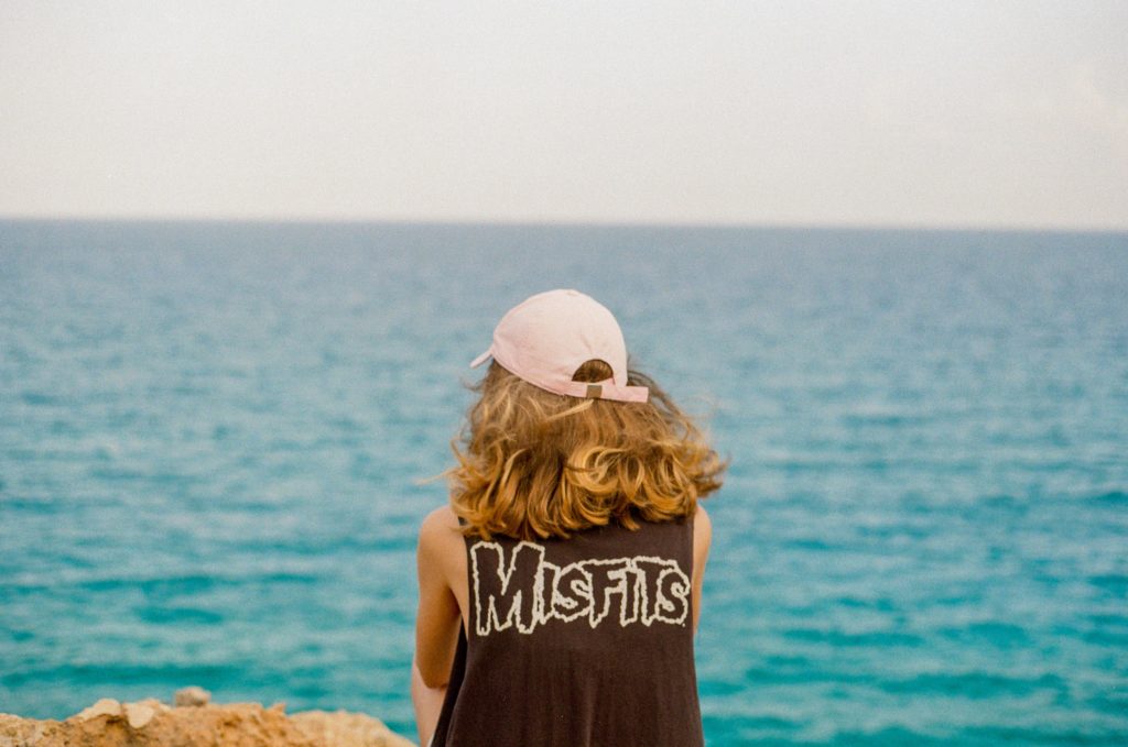 Woman sitting by herself on the beach wearing a Misfits shirt.