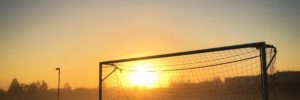 The sun peeks over the horizon behind the silhouette of a soccer goal on a foggy morning. Learn about the personality characteristics of the best athletes, coaches, and teams.
