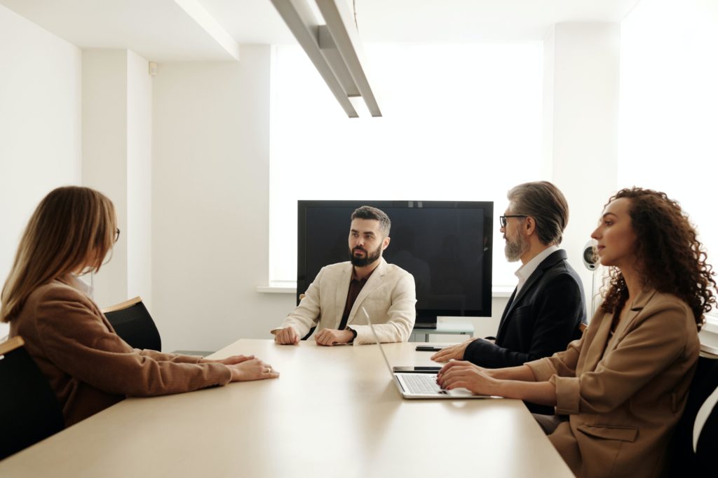 Three interviewers and one job candidate sit around a table in a conference room. 