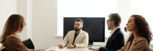 Three interviewers and one job candidate sit around a table in a conference room.