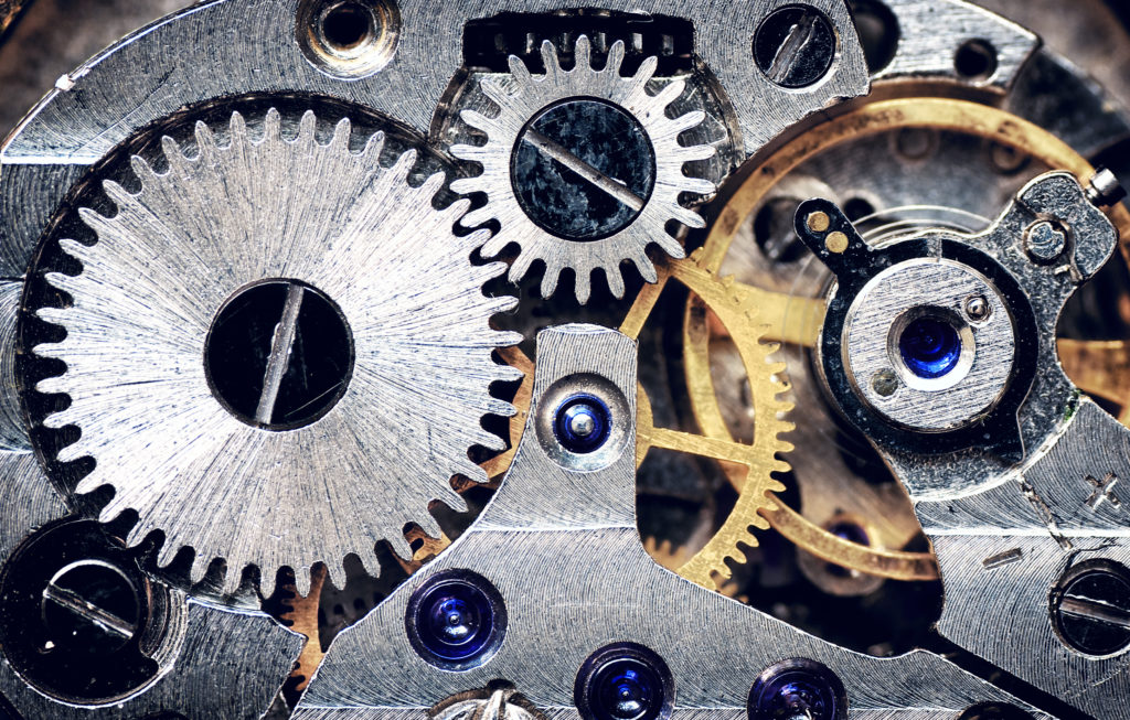A close-up of a clock mechanism’s steel and metal gears signifies the many features that determine how personality tests work.