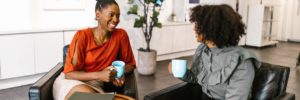 Two women leaders sip coffee in an office, highlighting one of the benefits of leadership development: networking.