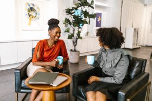 Two women leaders sip coffee in an office, highlighting one of the benefits of leadership development: networking.