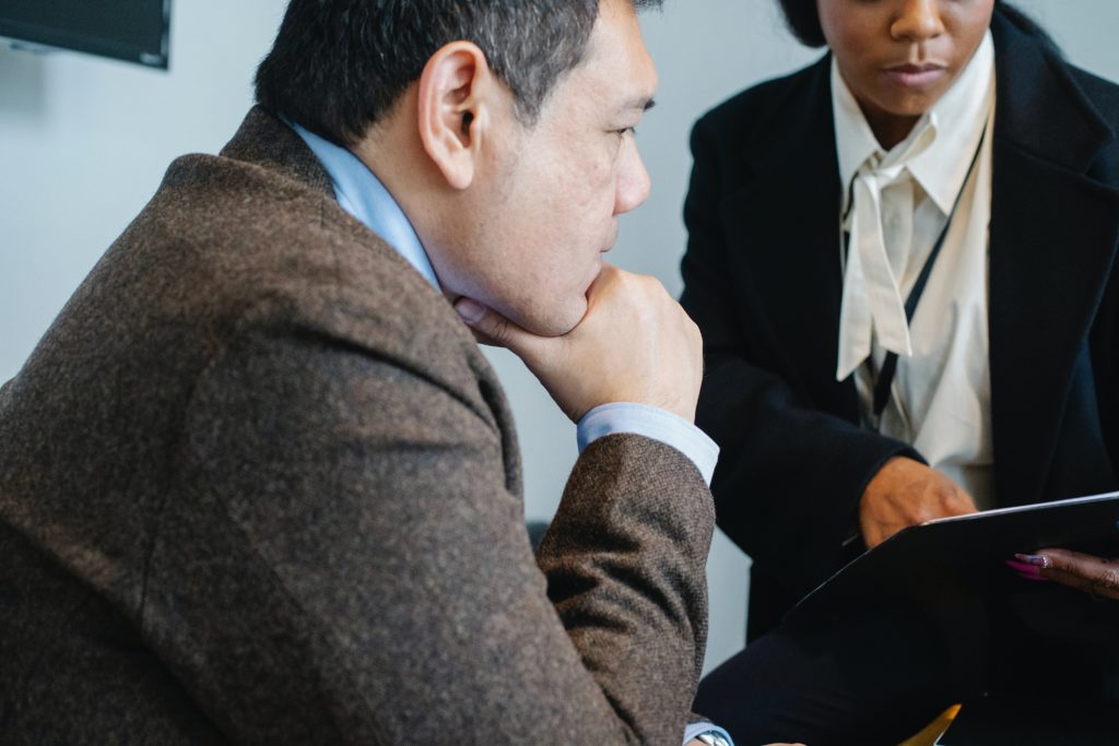 Two people in business attire discuss the contents of a binder for a leadership development program.