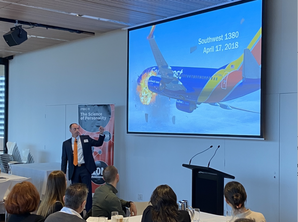 During a July 2022 presentation for Peter Berry Consultancy, Ryne Sherman, PhD, chief science officer for Hogan, gestures at a projector screen displaying Southwest Airlines Flight 1380 during its engine failure on April 17, 2018. Sherman’s presentation focused on the personality characteristics of people who show effective leadership through organizational crisis. Flight 1380 was piloted by Tammie Jo Shults, who is an excellent example of a crisis-resilient leader. 