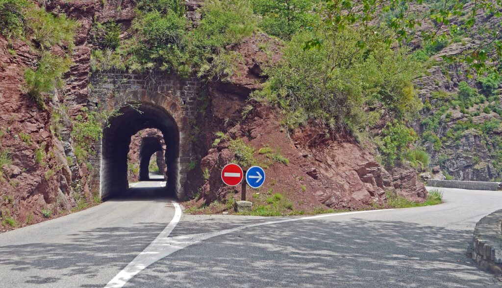 A crossroads of two distinctly different mountain passes, one roundabout and one straight through a tunnel, illustrates the idea of a reskilling strategy involving socioemotional skills.