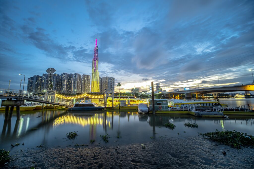 The lights of the Ho Chi Minh City skyline reflect on the harbor. The sun is below the horizon, so the sky is somewhat dark. The photo illustrates a blog about Hogan CEO Scott Gregory’s recent trip to Ho Chi Minh City, where he visited Talent Assessments Vietnam and gave presentations on leadership.