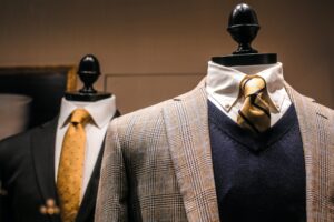 Two headless mannequins wear mens suits. The photo accompanies a blog post about leadership emergence versus leadership effectiveness. The latter is the ability to build a high-performing team. The former is about charisma and politics and explains why and how C-suites and boardrooms are mostly filled with men named John. The empty suits signify the appearance of leadership without true effectiveness.