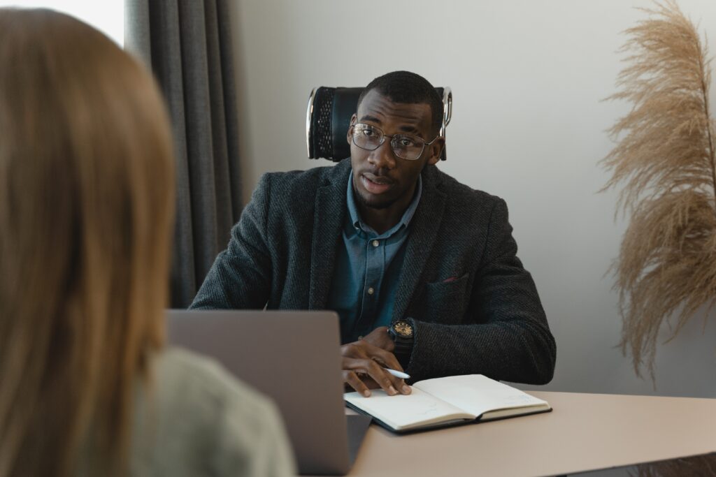 A professional coach at a small conference table converses with a business leader. The photo accompanies a blog post about how to overcome feedback resistance.