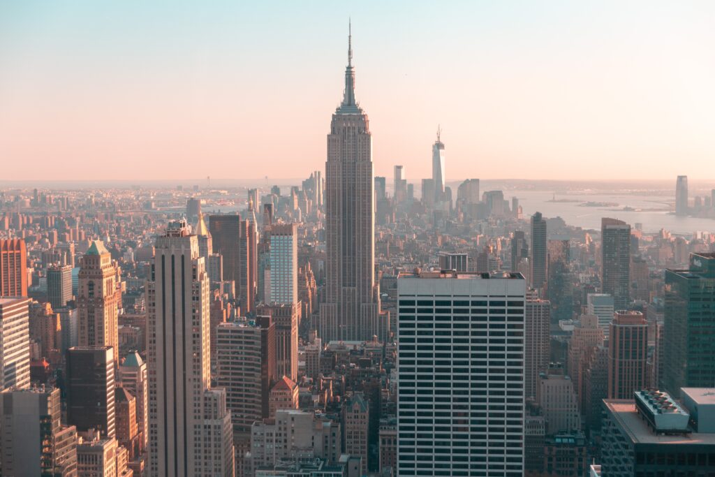 A photo of the New York City skyline glowing pink at dusk or dawn. The photo accompanies a statement about Hogan's position on NYC Local Law 144.