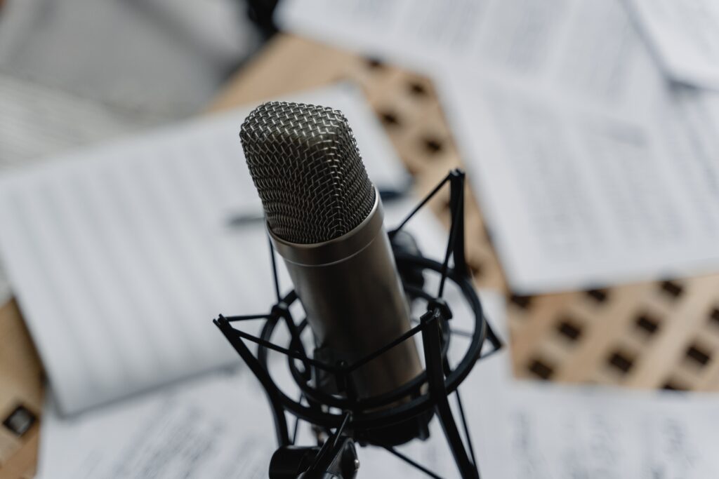 A close-up photograph of a studio microphone. In the background, which is out of focus, scattered papers lie across a tabletop. The image accompanies a blog post about the top five episodes of the Science of Personality podcast from its first three years.