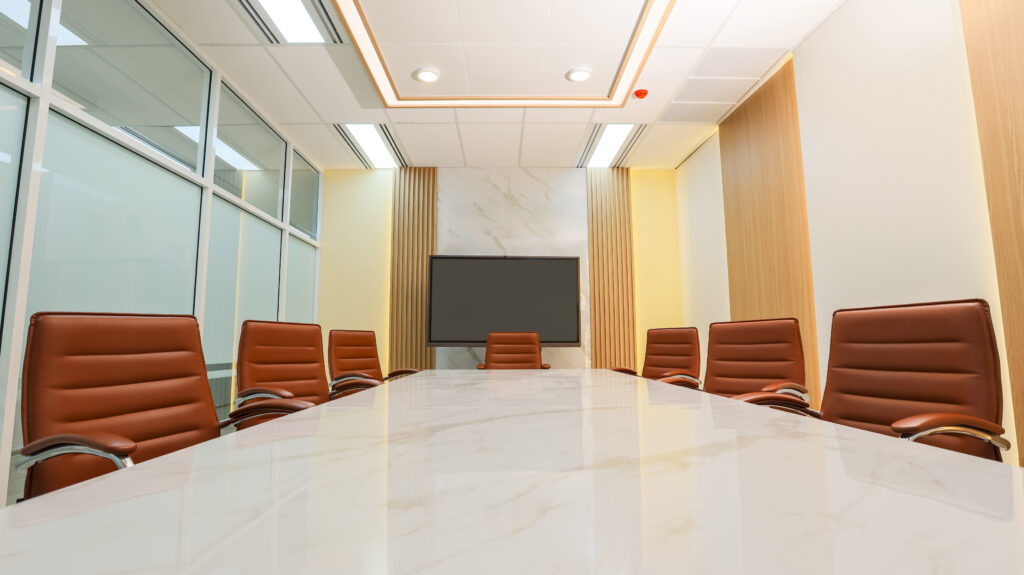 An empty board room has cognac leather chairs circling a marble-topped conference table. Centered in the photo is a large-screen monitor against a marble wall panel. The conference room wall at the left of the frame is glass-paneled, whereas the wall at the right is paneled with alternating wood and white drywall or plaster. The room is brightly lit. The photo accompanies a blog post about talent acquisition strategy, executive coaching, and getting the right talent into the right seats.