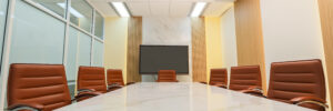 An empty board room has cognac leather chairs circling a marble-topped conference table. Centered in the photo is a large-screen monitor against a marble wall panel. The conference room wall at the left of the frame is glass-paneled, whereas the wall at the right is paneled with alternating wood and white drywall or plaster. The room is brightly lit. The photo accompanies a blog post about talent acquisition strategies, executive coaching, and getting the right talent into the right seats.