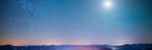 A landscape of a wintry mountain range against a starry night sky with a bright full moon. Amid the mountains is a glowing light, conceptualizing the mysticism of UFOs and abnormal phenomena.