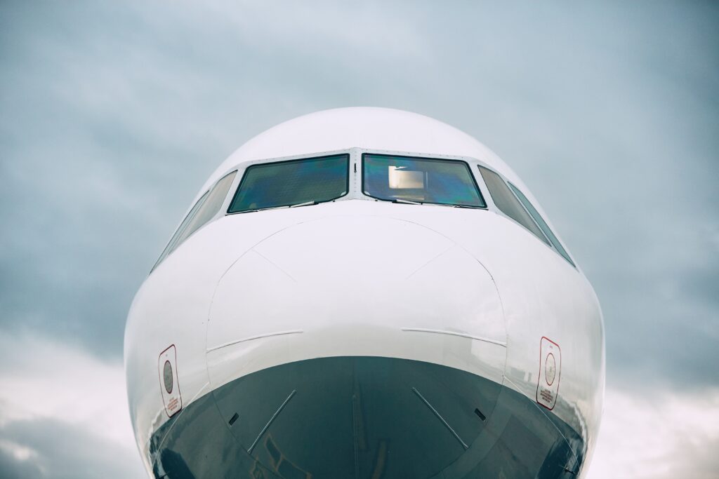 The photo displays a frontal view of an unmarked airplane nose against a cloudy sky. The photo accompanies a blog post about pilot personality, the pilot shortage, hiring the best talent for pilot jobs, and developing successful pilots.
