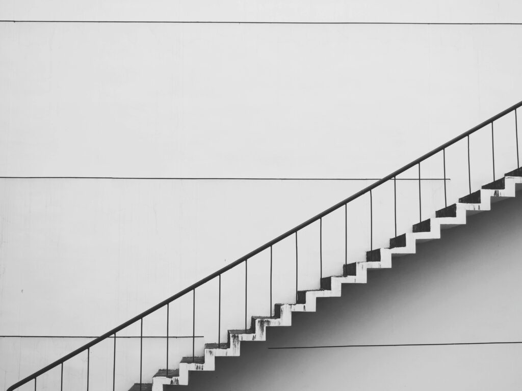 A monochrome image of a staircase, showcasing the contrasting shades of black and white, accompanies a blog post about adapting leadership development strategies across managerial levels.