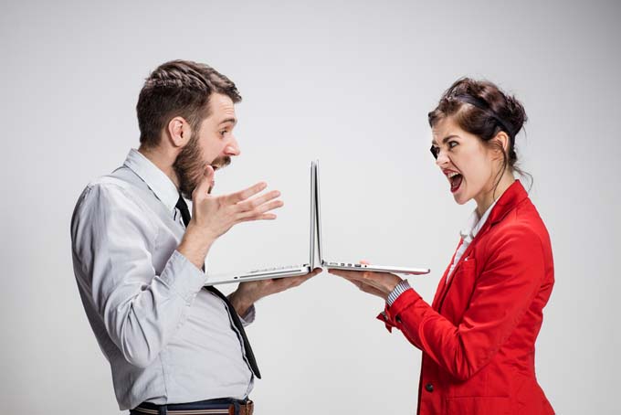 The young businessman and businesswoman with laptops on gray background