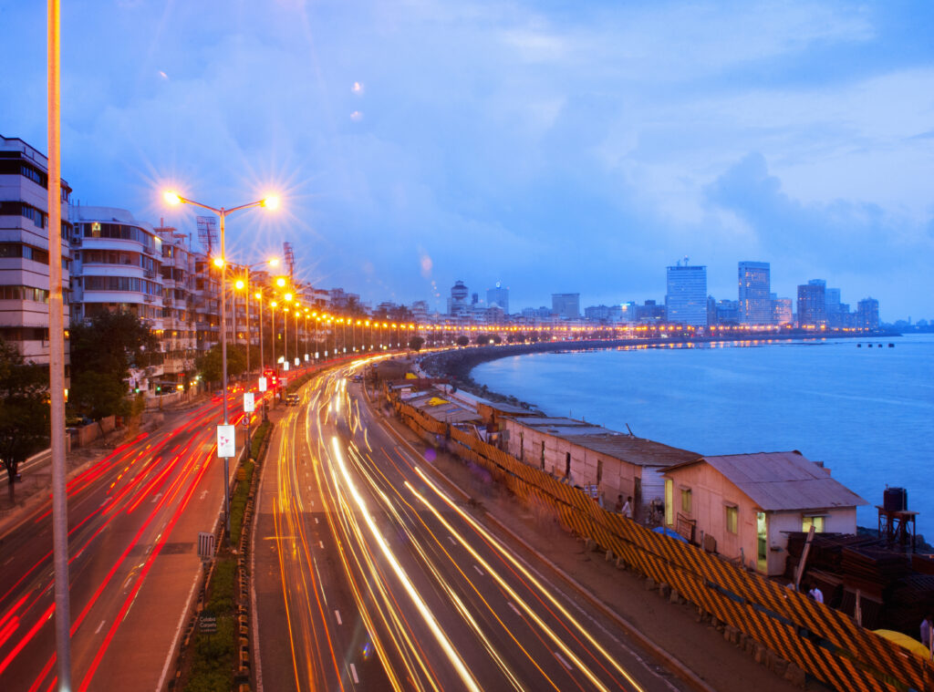 Glimmering lights trace the curve of the Queens Necklace coastal road in Mumbai, India, as the city’s skyscrapers rise in the distance. This image accompanies an article about leadership trends in India