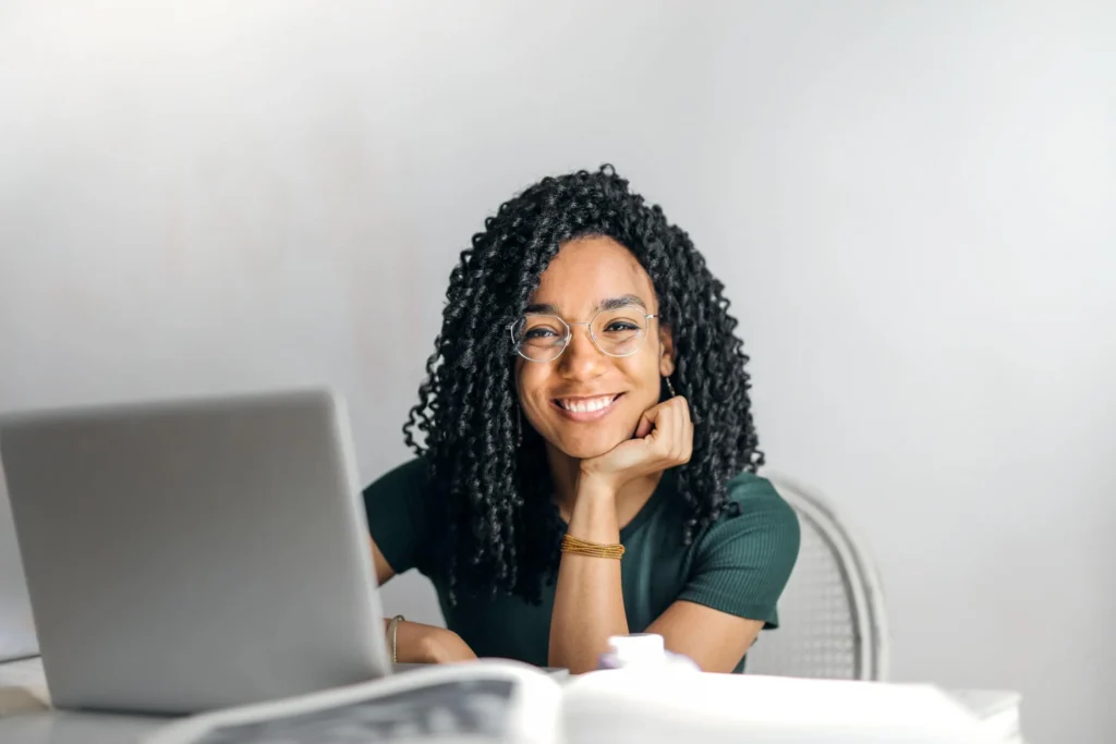 woman in green shirt sitting at a desk with a laptop