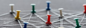 panoramic shot of colorful push pins connected with strings isolated on grey, network concept