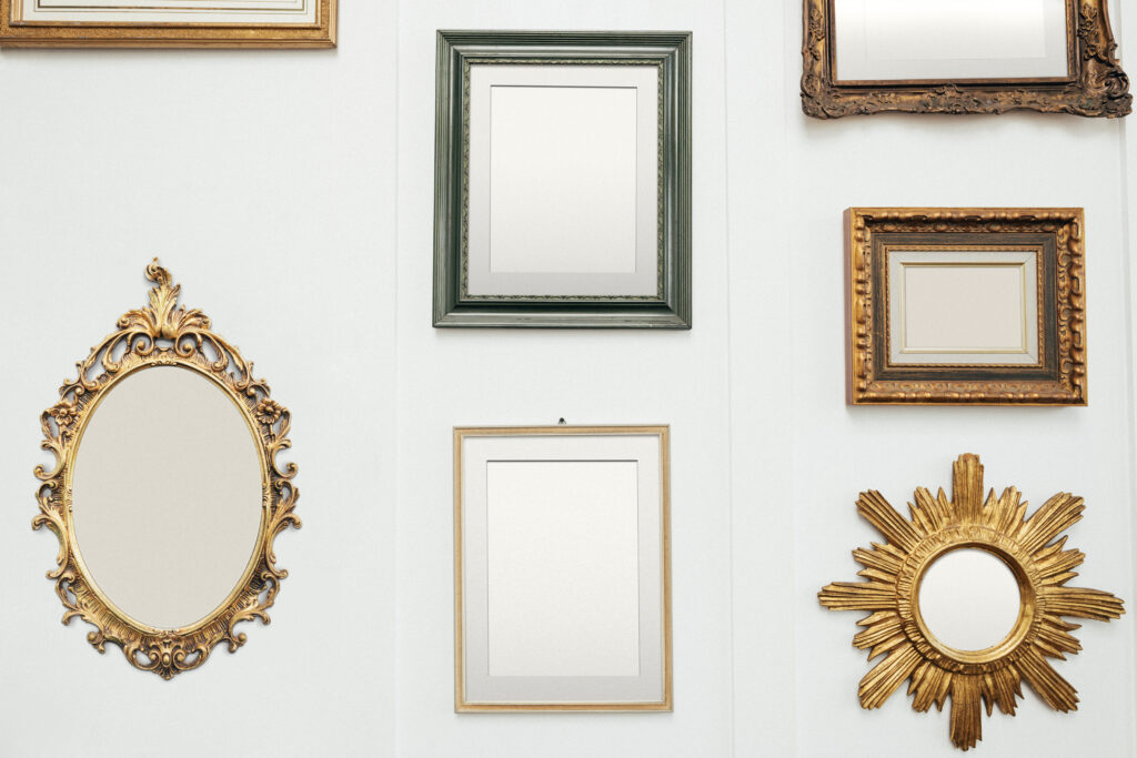 A variety of empty picture frames are arranged on a gallery wall
