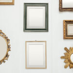 A variety of empty picture frames are arranged on a gallery wall