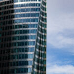 A glass skyscraper reflects the ominous shadow of another skyscraper, which is out of frame. The image accompanies an article about how the dark side of leadership tends to manifest in executives.