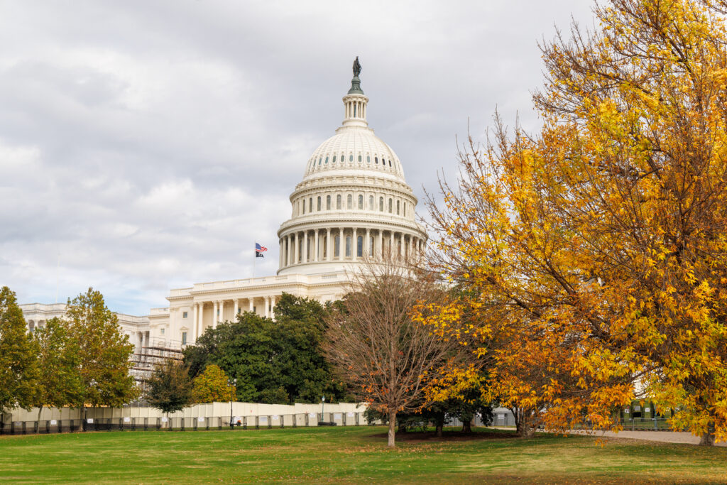The iconic white dome of the US Capitol in Washington, DC, is shown surrounded by vibrant gold and orange autumn foliage. The image accompanies an article about personality trends of US executives.