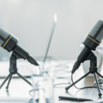 A podcast recording setup shows two microphones positioned across from each other in a bright, minimalist workspace. The image accompanies an article about The Science of Personality podcast listener questions.
