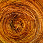 A long-exposure photograph depicts counterclockwise spiraling lines of gold and white light against a black background. The image suggests a creative yet unfocused state of mind, a metaphor for the Hogan Development Survey Imaginative scale derailer.