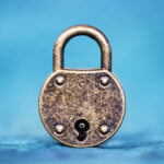 An aged, gold-toned metal padlock against a blue background. This image accompanies an article about five steps to a better high-potential program.