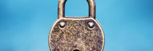 An aged, gold-toned metal padlock against a blue background. This image accompanies an article about five steps to a better high-potential program.