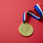 Gold medal. Champion trophy award and ribbon. Prize in sport for winner isolated on red background