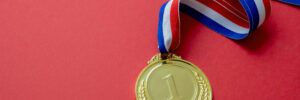 Gold medal. Champion trophy award and ribbon. Prize in sport for winner isolated on red background