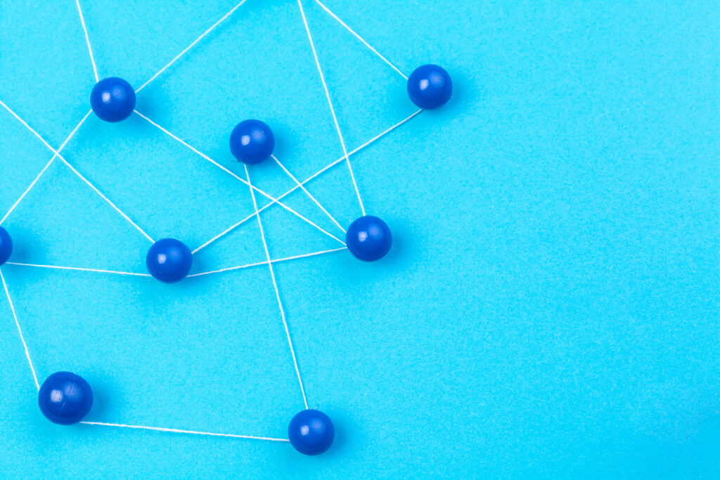 Blue pins connected by white string are linked together network-style against a light blue background. The image accompanies an article about the complexity of team communication at work.