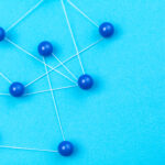 Blue pins connected by white string are linked together network-style against a light blue background. The image accompanies an article about the complexity of team communication at work.