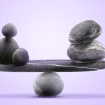Two stacks of gray stones balance on either end of a flat stone slab balanced atop a single round rock against a purple gradient background. The image accompanies an article about balancing psychological safety and team engagement.