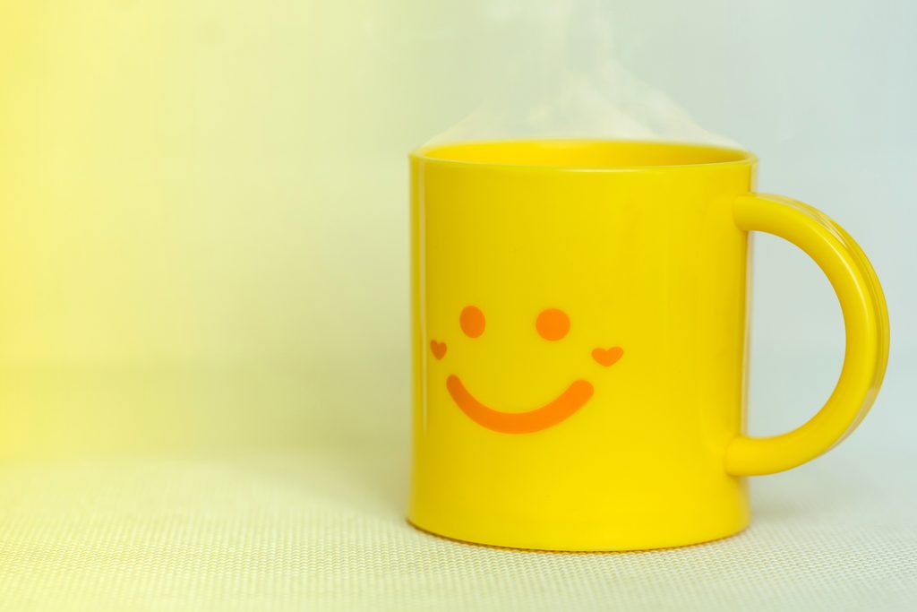 A yellow mug with a smiley face design signifies the outward agreement and passive aggression associated with Leisurely derailment. The image accompanies a blog post about working with passive-aggressive leaders.